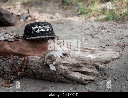 06. August 2020 , Altay Republik, Russland: Verlorene Baseballmütze an einem Strand mit Bergsee Sand und Müll mit Notiz in englischer UNDERGROUND LO Stockfoto
