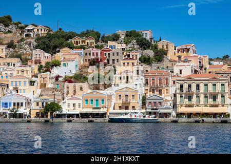 SYMI, Griechenland - 03. JUNI 2021. Der Hafen von Symi Stadt mit den Bezirken Chorio und Gialos ist einer der schönsten und romantischsten in der ganzen A Stockfoto