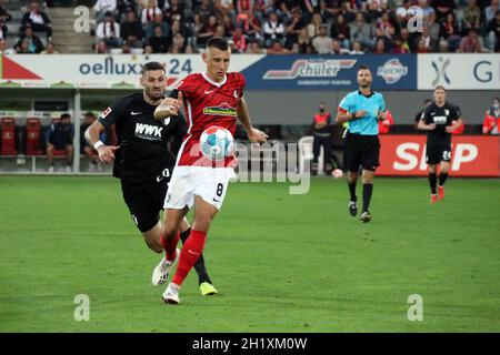 v. li. Im Zweikampf gegen# Daniel Caligiuri (FC Augsburg) und Maximilian Eggestein (SC Freiburg), 1. FBL: 21-22: 6. Spt. SC Freiburg gegen FC Augsburg D Stockfoto