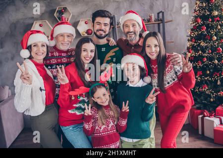 Fotoportrait große Familie ältere kleine Generationen feiern gemeinsam Weihnachtsfeiertage mit V-Zeichen Stockfoto