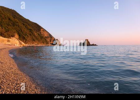 Blick auf den Strand und den Asseu-Felsen in Riva Trigoso (Italien) bei Sonnenuntergang. Bis 2020 war es möglich, den Felsen über eine Promenade zu erreichen. Speicherplatz kopieren. Stockfoto