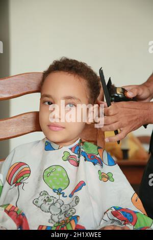 salvador, bahia, brasilien - 18. oktober 2021: Kind schneidet Haare in einem Wohnsitz in der Stadt Salvador. Stockfoto