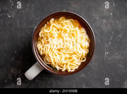 Instant Nudeln in Tasse auf dem rustikalen Hintergrund. Selektiver Fokus. Geringe Schärfentiefe. Stockfoto