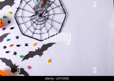 Komposition von halloween Dekorationen mit Spinnennetz, Fledermäusen und Süßigkeiten auf weißem Hintergrund Stockfoto