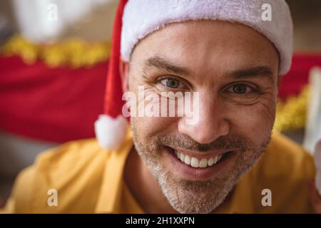 Porträt eines kaukasischen Mannes mit weihnachtsmütze, der während der weihnachtszeit zu Hause lächelt Stockfoto