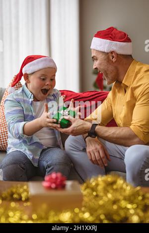 Der kaukasische Vater schenkte seinem Sohn zu Hause zu weihnachten ein weihnachtsgeschenk Stockfoto