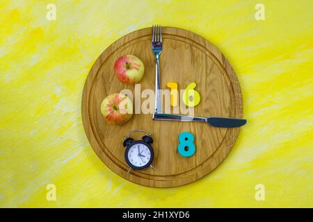 Intermittierendes Fasten 16:8 Uhr. Gesunde Ernährung Lebensstil mit beliebten Gesundheits-und Fitness-Trend. Flach liegend. Gelber Hintergrund Stockfoto