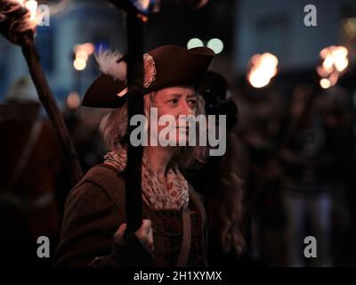 Eine Fackel trägt eine Frau im historischen Kleid Kostüm - Hastings Borough Bonfire Society HBBS Fackelzug - 16. Oktober 2021 East Sussex UK Stockfoto