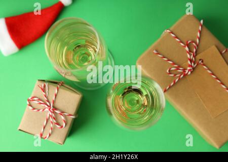 Gläser Champagner, Weihnachtsmütze und Geschenkschachteln auf grünem Hintergrund. Stockfoto
