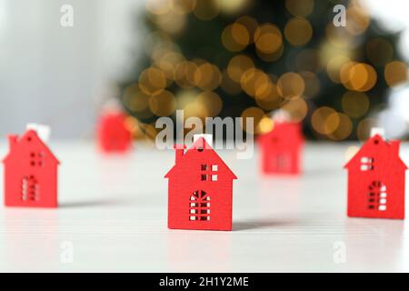 Weihnachtskonzept mit roten Häusern auf weißem Holztisch auf unscharfem Lichthintergrund. Stockfoto