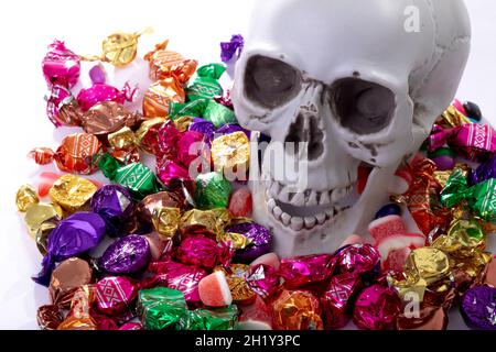 Komposition von halloween Lachschädel mit Trick or Treat Süßigkeiten auf weißem Hintergrund Stockfoto