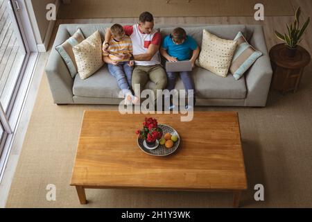 Ansicht von oben auf kaukasischen Vater und zwei Söhne mit Laptop und digitalem Tablet zu Hause Stockfoto