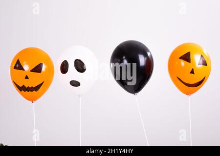 Orangefarbene, schwarz-weiße halloween-Ballons auf weißem Hintergrund Stockfoto