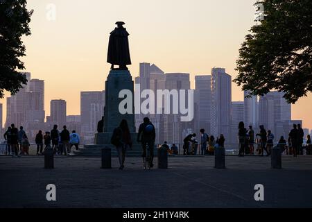 Menschen, die den Sonnenuntergang im Greenwich Park mit den Wolkenkratzern von Canary Wharf im Hintergrund beobachten, London, England, Großbritannien Stockfoto