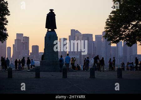 Menschen, die den Sonnenuntergang im Greenwich Park mit den Wolkenkratzern von Canary Wharf im Hintergrund beobachten, London, England, Großbritannien Stockfoto