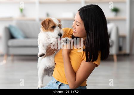 Nahaufnahme einer attraktiven asiatischen Frau, die mit ihrem Hund kuschelt Stockfoto