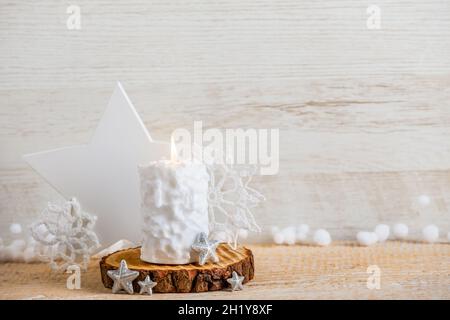 Vintage nordischen Stil minimalistischen Weihnachtshintergrund mit viel Platz für Kopien. Selektiver Fokus auf Schneeballmuster weiße Kerze brennend, Sternform. Stockfoto