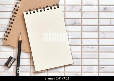 Offenes leeres Notizbuch, Bleistiftspitzer und Bleistift auf weißem Hintergrund, Flat Lay-Konzept, Copy Space for Text, Tabellenansicht oben. Stockfoto