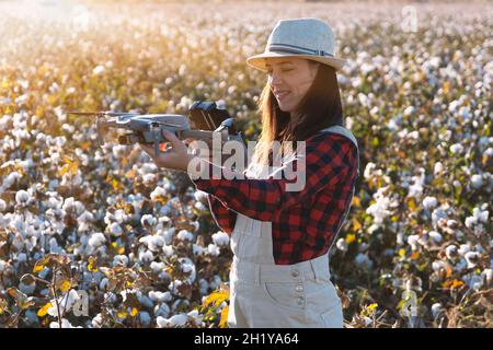 Die weibliche Drohnenpilotin geht ins Feld und inspiziert vor dem Flug. Drohne in Frauenhand. Landwirtin überprüft landwirtschaftliche Produktivität usin Stockfoto