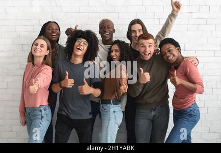 Glückliche Millennials verschiedener Nationalitäten zeigen Daumen nach-ups Stockfoto