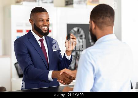 Schwarzer Verkäufer Und Männlicher Kunde Schütteln Sich Nach Dem Deal Im Händlerzentrum Die Hände Stockfoto