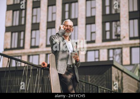 Ein grauhaariger Mann mit einem Gadget in den Händen Stockfoto