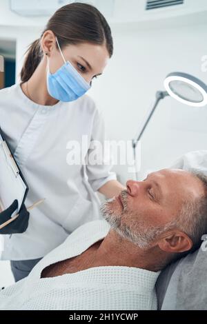 Kosmetikerin mit Blick auf männliche Klientin in der Kosmetologie-Klinik Stockfoto