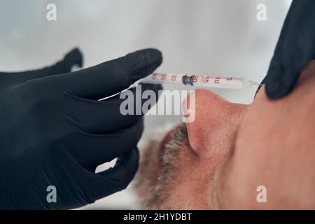Kosmetologe Hände machen Injektion im männlichen Gesicht Stockfoto