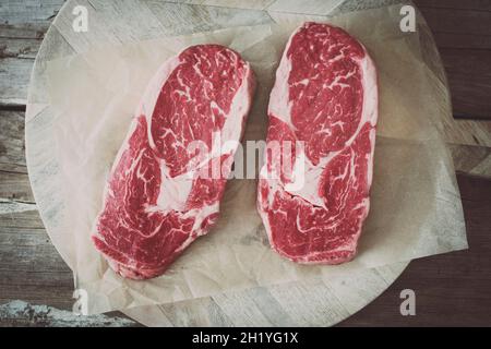 Rohe Ribeye-Steaks auf einem Stück Papier Stockfoto