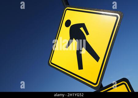 Eine kühne und farbenfrohe Szene mit einem hellgelben Straßenschild (das eine menschliche Form beim Gehen zeigt), das einem tiefblauen Himmel entgegengesetzt ist. Stockfoto
