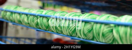 Reihen von Kugeln aus bunten Baumwollgarn Fäden zum Stricken melange gestreiften grün weißen Farben auf den Regalen im Geschäft. Banner Stockfoto
