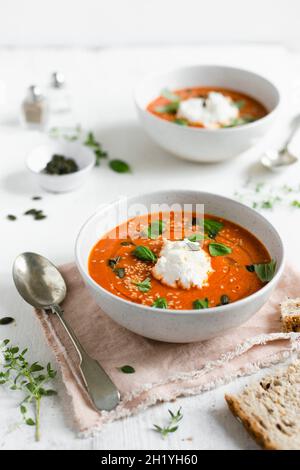 Eine Schüssel gebratene Tomatensuppe mit frischem Basilikum, Ricotta und gerösteten Samen Stockfoto