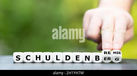 Hand dreht Würfel und ändert das deutsche Wort 'Schuldenberg' in Schuldenbremse. Stockfoto