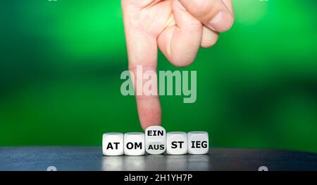 Die Hand dreht Würfel und ändert das deutsche Wort 'Atomausstieg' in 'Atomeinstieg'. Stockfoto