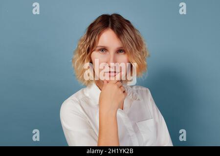 Die Frau dachte, sie rieb sich mit der Hand das Kinn. Frau Porträt vor festem Hintergrund Stockfoto