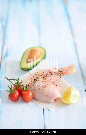 Ein gewürztes Hühnerbein mit Kirschtomaten, Zitrone und Avocado Stockfoto