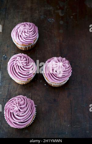 Vier Blaubeer-Cupcakes auf einem dunklen Holztisch Stockfoto
