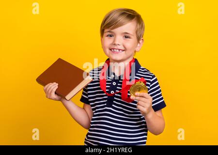 Foto Porträt kleiner Junge trägt goldene Medaille Preis für beste Schüler isoliert lebendige gelbe Farbe Hintergrund Stockfoto