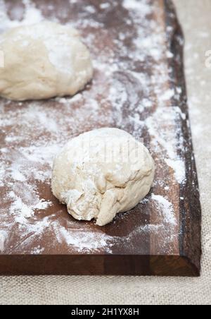 Pizzateig mit Mehl auf einem Holzbrett Stockfoto