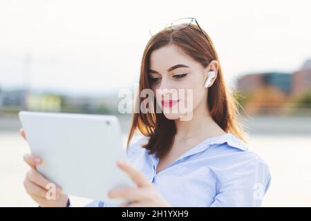 Junge kaukasische Frau mit Headset mit Tablet im Freien Stockfoto