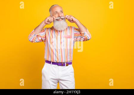 Porträt von attraktiven fröhlich grauhaarigen Mann berühren Schnurrbart Denken isoliert über hellen gelben Hintergrund Stockfoto