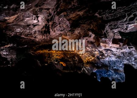 Dunkle, farbenfrohe Wandtexte in einer Lavaröhre der Insel Canaria. Stockfoto