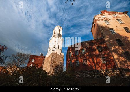 Vyborg, Russische Föderation - 6. Oktober 2021; Vyborg Clock Tower, ein ehemaliger Glockenturm, neben einem roten Backsteinhaus in der Stadt Vyborg Stockfoto