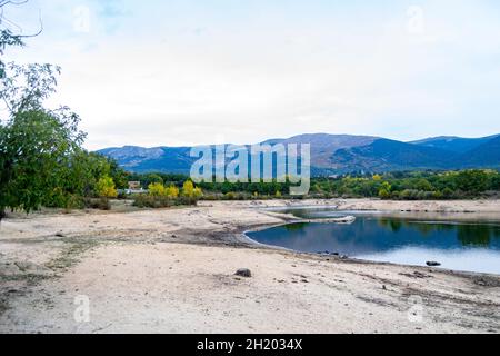 Blick auf einen Stausee, der die Landschaft im Wasser an einem bewölkten Tag in Segovia, in Castilla y León, in Spanien widerspiegelt. Europa. Horizontale Fotografie Stockfoto