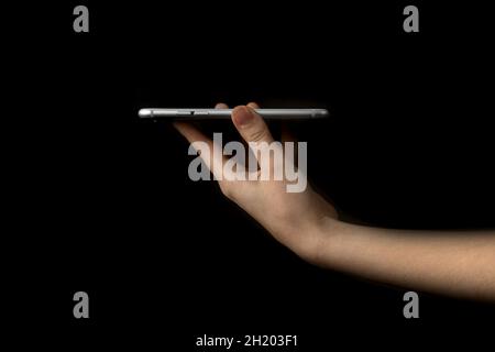 Person hält in der Hand Mobiltelefon, isoliert auf schwarzem Hintergrund, Präsentation Modell Vorlage Konzept Stockfoto