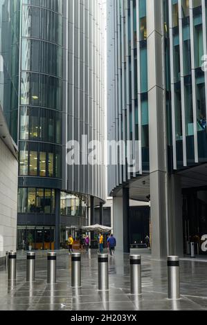 Eine Gruppe von Touristen, die an einem nassen Oktobertag zwischen Bürogebäuden in der Lime Street in der City of London, England, spazieren. Stockfoto