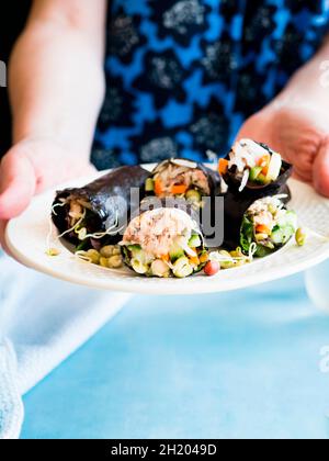 Eine Frau, die einen Teller mit Nori-Wraps anbietet Stockfoto