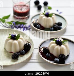 Veganer Zitronen- und Kokosnusspudding mit Brombeersauce, frischen Brombeeren und Heidelbeeren Stockfoto