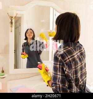 Die junge Frau wascht im Badezimmer den Spiegel. Stockfoto