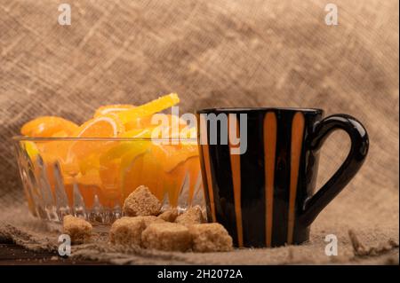 Bunte, geformte Marmeladenscheiben in einer Glasvase, Stücke braunen Rohrzuckers und eine Tasse Kaffee, Nahaufnahme, selektiver Fokus Stockfoto